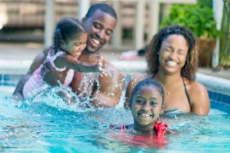 Family enjoying time together in a swimming pool while practicing swim safety.