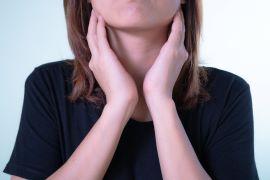 Girl with hands on side of neck feeling throid gland area